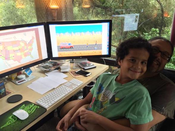 Donovan Romero, age 10, and John Romero, Brenda's husband, showcasing Donovan's own game, Gunman Taco Truck.